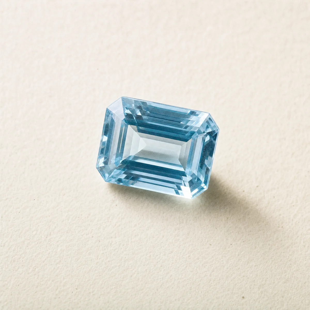 Emerald-cut pale blue aquamarine on white gem paper