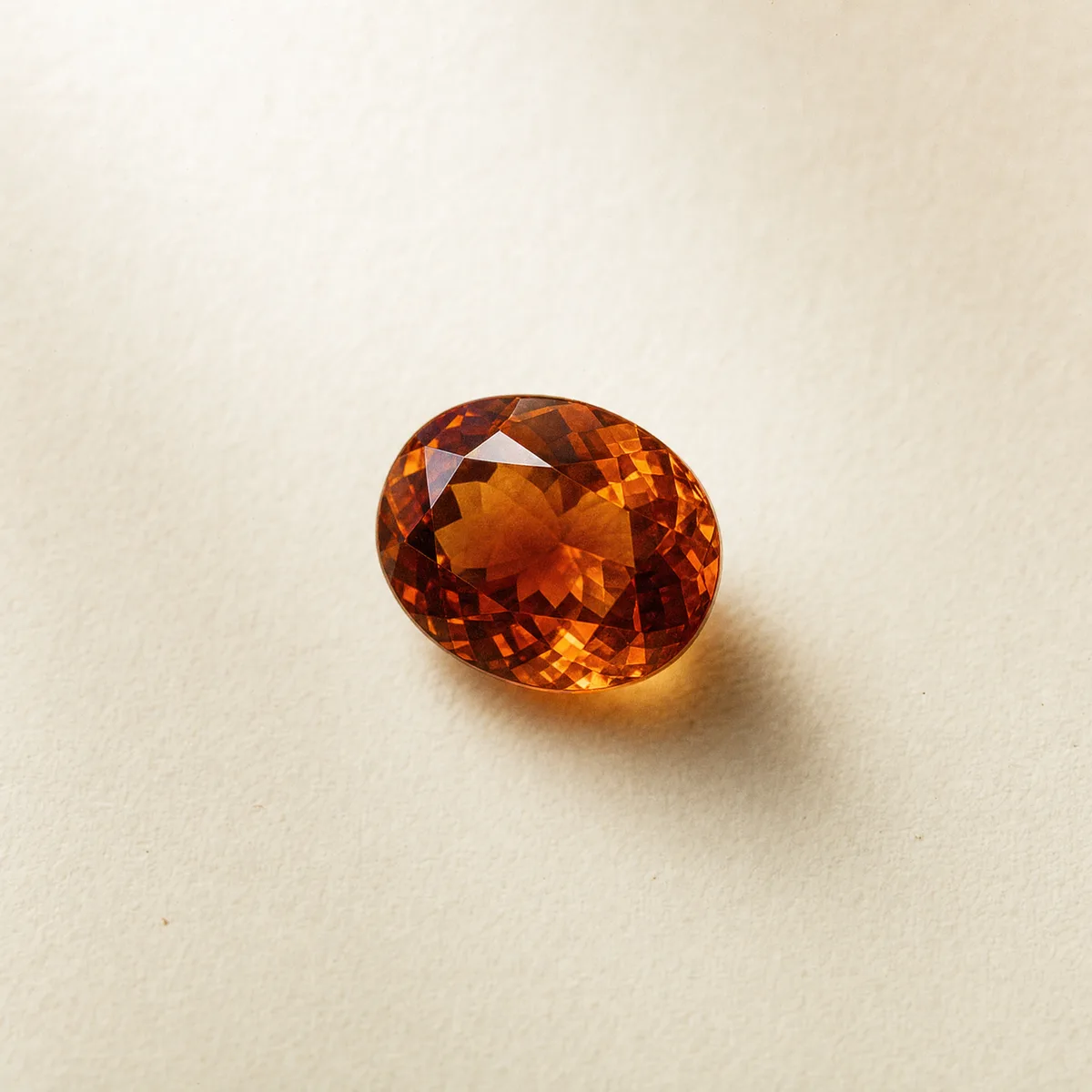 Oval-cut cinnamon hessonite garnet on white gem paper
