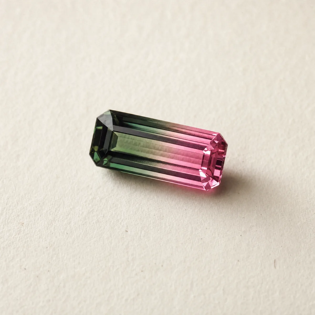 Emerald-cut bi-color tourmaline, green to pink, on white gem paper
